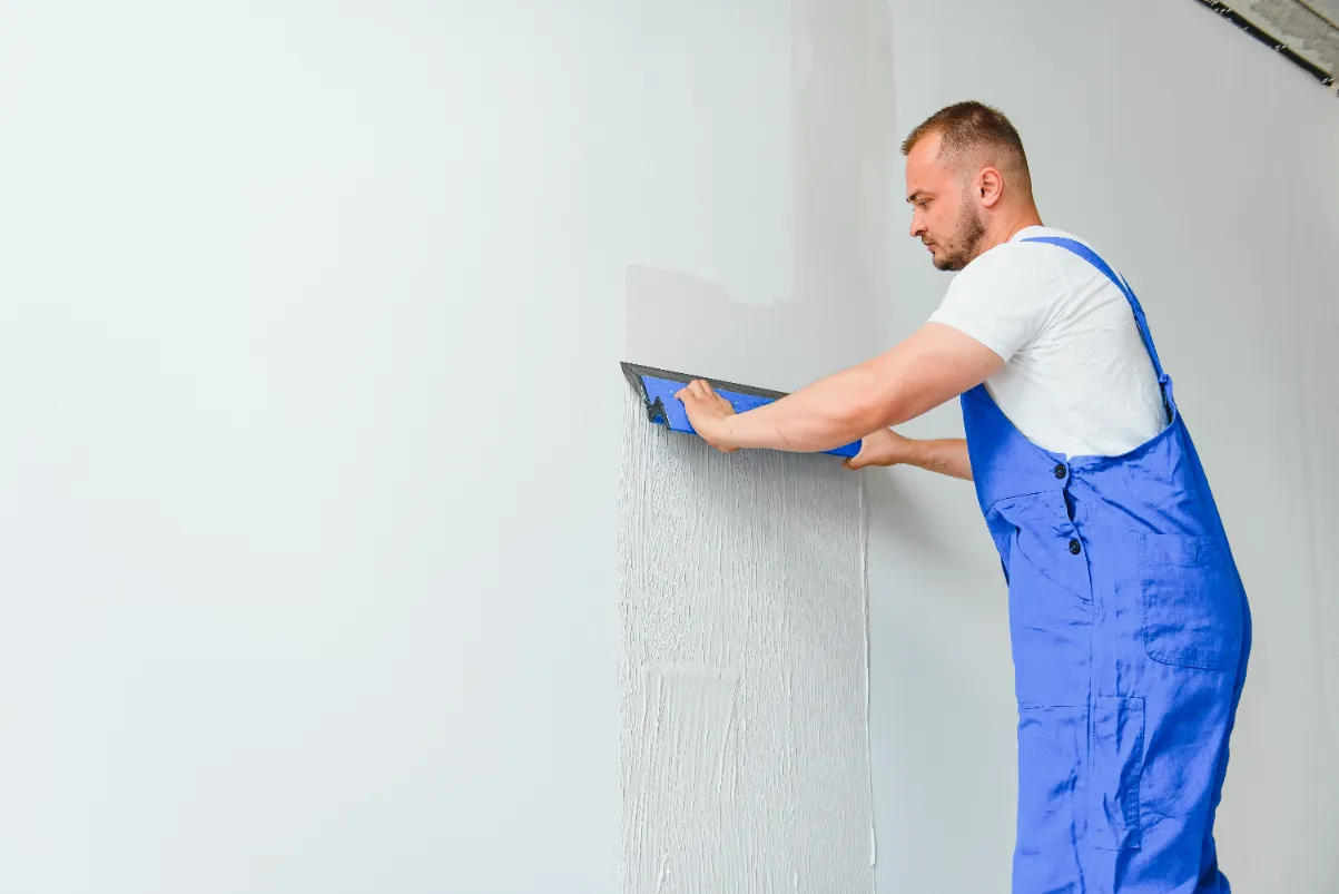A worker carefully finishing the drywall.