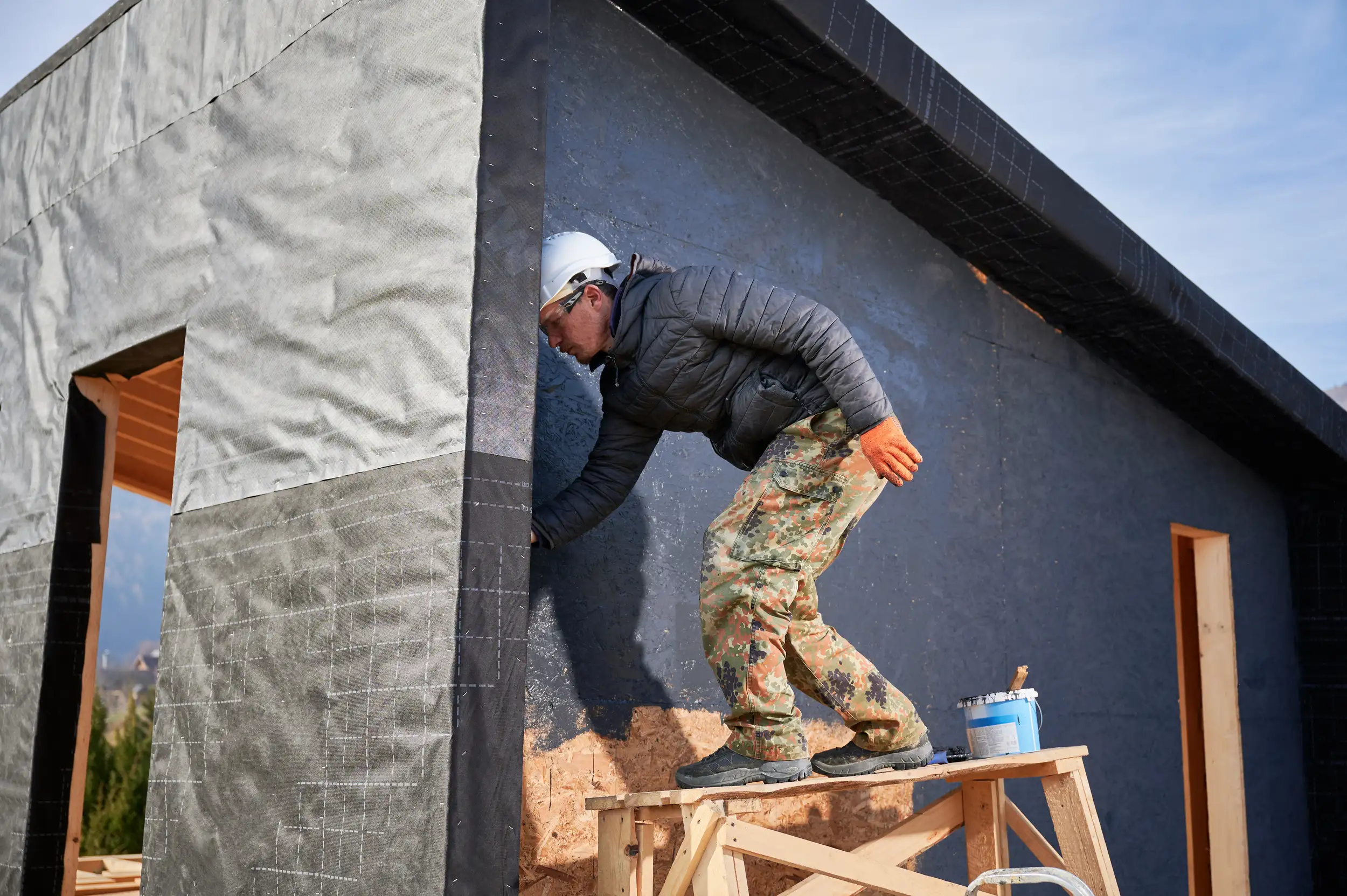 A male painter painting the outside wood wall of the house.