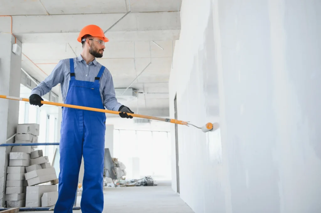 A man painting the wall with a paint roller.