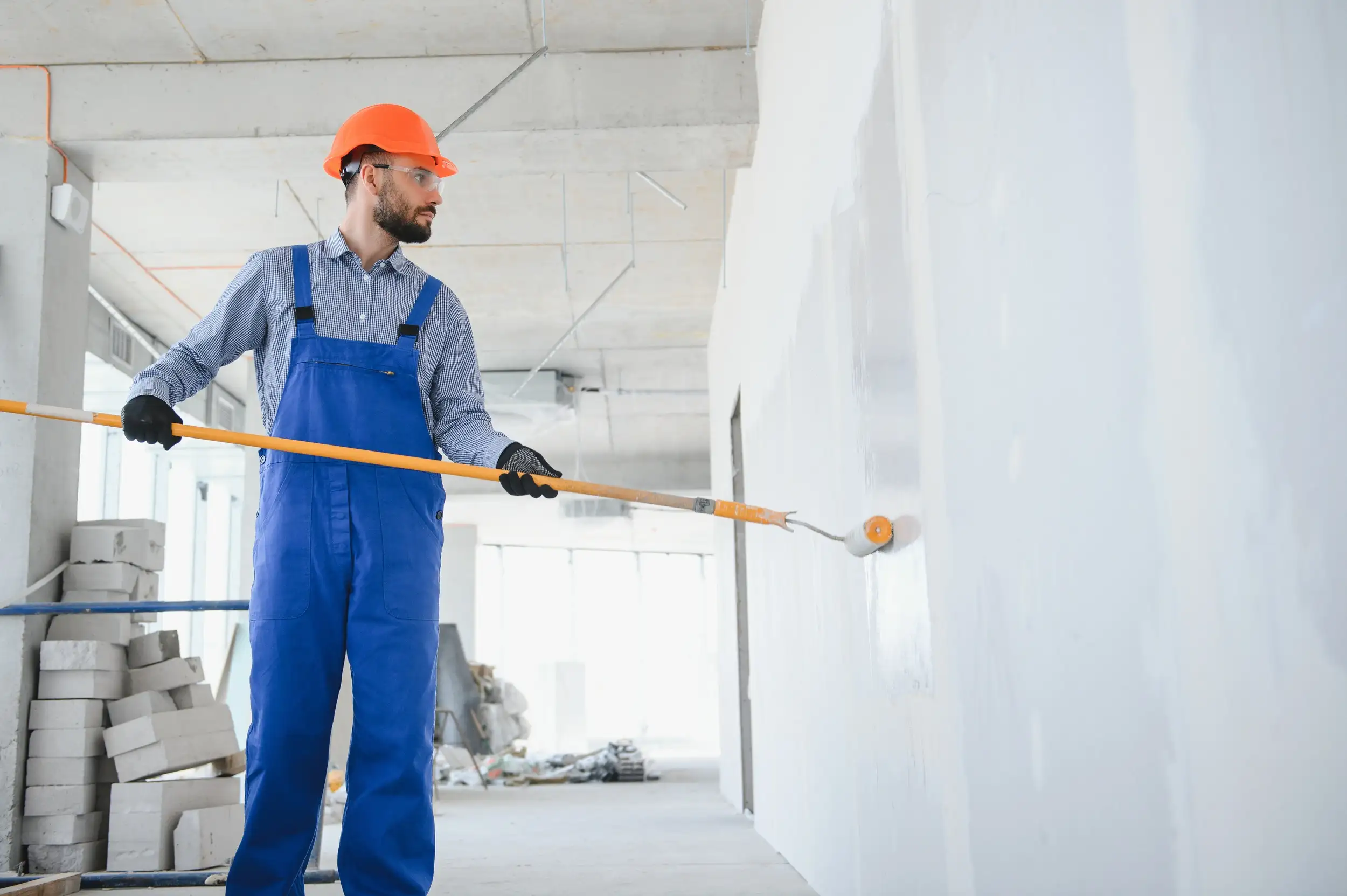 A man painting the wall with a paint roller.